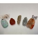 A group of five various coloured jade and carved hard stone Chinese pendants including pale