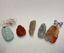 A group of five various coloured jade and carved hard stone Chinese pendants including pale