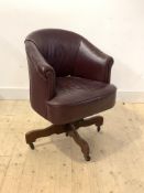 An early 20th century leather upholstered tub shaped desk chair, reclining and on a swivel base with