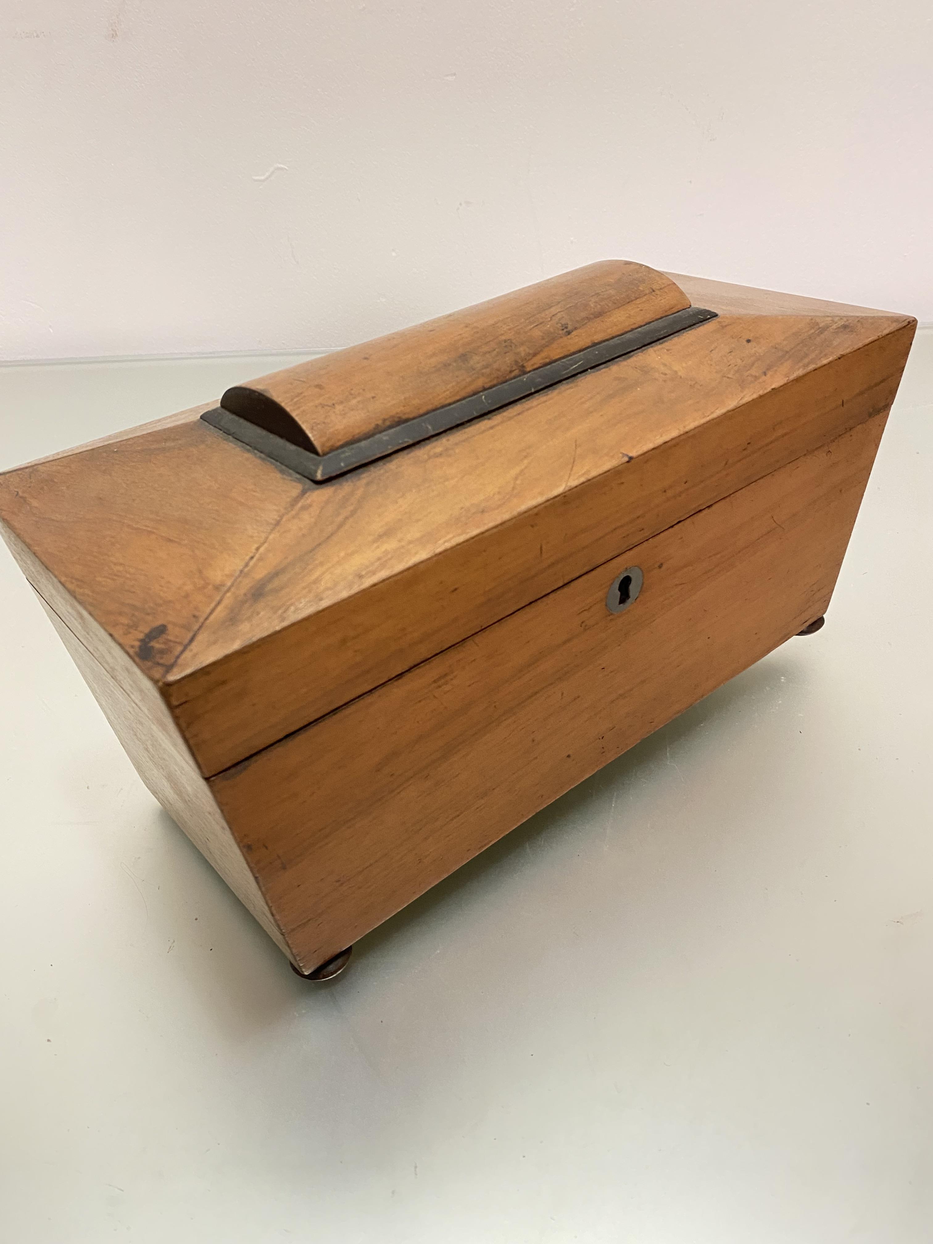 A 19thc walnut sarcophagus shaped tea caddy, the interior fitted with centre open aperture flanked