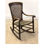 A 19th century mahogany rocking chair, the cane back over open arms with turned arm terminals,