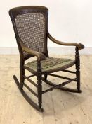 A 19th century mahogany rocking chair, the cane back over open arms with turned arm terminals,