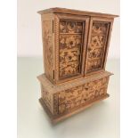 A late 19thc treen carved miniature cabinet bookcase with a pair of panelled doors, missing glass,
