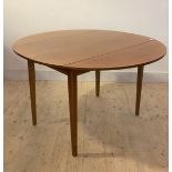 A mid century teak drop leaf dining table, with circular top raised on sqaure tapered supports,
