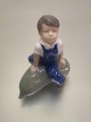 A Royal Copenhagen Danish porcelain figure of a boy on a marrow decorated with polychrome enamels (