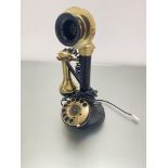 A modern reproduction brass and black composition candlestick style telephone with numerical dial,
