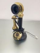 A modern reproduction brass and black composition candlestick style telephone with numerical dial,