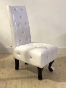 A Contemporary bedroom chair, upholstered in diomonte studded white faux leather, raised on ebonised