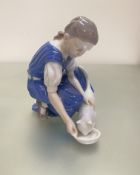 A Bing and Grondahl Danish porcelain figure of a young girl feeding her cat, decorated with