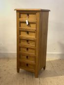 A modern polished pine tall chest fitted with seven drawers, raised on square tapered stile