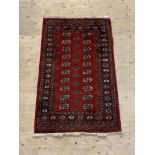 A hand knotted bokhara rug, the red field with two rows of guls enclosed by a border, 158cm x 97cm