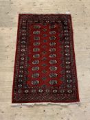 A hand knotted bokhara rug, the red field with two rows of guls enclosed by a border, 158cm x 97cm