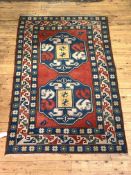 A Turkish hand knotted rug, the red field with double medallion, with geometric design to multi line