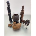 A collection of carved wood figures including an African standing figure, aThai figure of a lady,