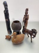 A collection of carved wood figures including an African standing figure, aThai figure of a lady,