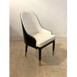 A Contemporary tub chair, upholstered in contrasting white and black faux leather, raised on