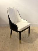 A Contemporary tub chair, upholstered in contrasting white and black faux leather, raised on