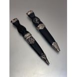 A pair of reproduction white metal faux ebony handled Sgian Dubh with white metal mounts and thistle