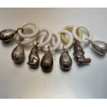 A collection of seven white metal chased child's rattles with composition teething rings, some in