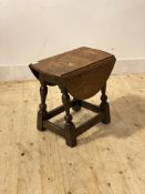 A 19th century oak drop leaf table, of an earlier design, with oval revolving top over turned and