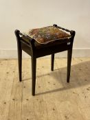 An Edwardian stained walnut music stool, with upholstered hinged top raised on square tapered