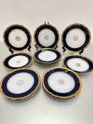 A set of twelve Limoges J Pouyat scalloped fruit plates with centre gilded panel enclosed within a