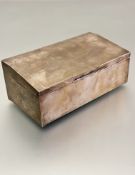 A silver cigarette box of rectangular form with engraved border and sloped top, enclosing a cedar