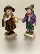 A pair of continental porcelain miniature figures of girl with green cape and a begging boy