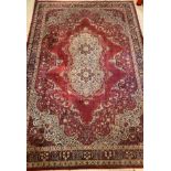 An Axminster Persian design carpet, the deep red field with ivory floral medallion and spandrels,