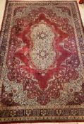 An Axminster Persian design carpet, the deep red field with ivory floral medallion and spandrels,