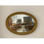 An Edwardian gilt composition framed oval wall mirror, the frame with egg and dart, fluting and