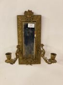 A late 19th century gilt brass mirrored wall sconce in the Neoclassical taste, with mask surmount