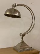 An Art Deco style silvered metal table light, the domed angle adjustable shade over bowed stretchers