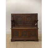 An early 20th century carved oak monks bench, the folding back over hinged seat and three panel