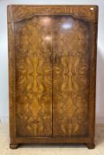 A 1920s figured walnut wardrobe, wit two doors enclosing a mirror, hanging rail and shelf, raised on