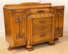An Art Deco oak credenza sideboard, with scrolled ledge back over four centre drawers and two
