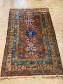 A hand-knotted Persian rug, with three lozenge medallions on a madder field, with stylised foliate