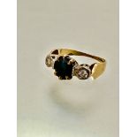 An 18ct gold three stone ring, set oval sapphire, table rubbed and scratched, mounted in claw