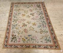 A Savonnerie style needlework rug or tapestry, the ivory field with floral motifs, framed within a