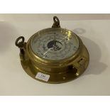 A brass ships bulkhead type aneroid barometer, with silvered dial and black pointer and vernier