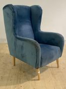 A contemporary wing chair, upholstered in blue crushed velvet, raised on turned beach supports,