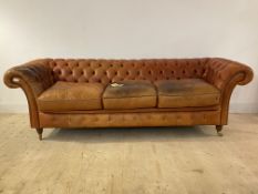 A large chesterfield sofa, upholstered in deep buttoned leather, raised on turned front supports