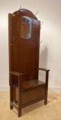 A 1930s oak veneered hall seat, with mirrored back six coat hooks, hinged seat and stile supports,