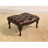 A deep buttoned and studded oxblood leather upholstered foot stool, raised on cabriole supports,