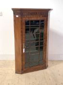 A George III mahogany wall hanging corner cabinet, with projecting cornice over a figured frieze,