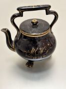 A Victorian black glazed pottery teapot highlighted with gold borders with gilded initials MEW 1875,