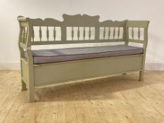 A continental hall bench, painted in a pale green, with shaped crest rail over spindle gallery,