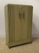 An Art Deco period green painted oak gentlemans compactum wardrobe, two doors with turned and