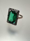 A 9ct gold and white metal mounted green paste set dress ring, the cushion-cut centre stone, the