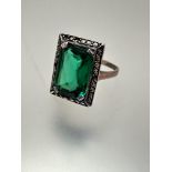 A 9ct gold and white metal mounted green paste set dress ring, the cushion-cut centre stone, the